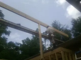 Carpenter setting a ridge beam over a new addition frame — Ice Dam Removal by Roofing Brothers in Langsville