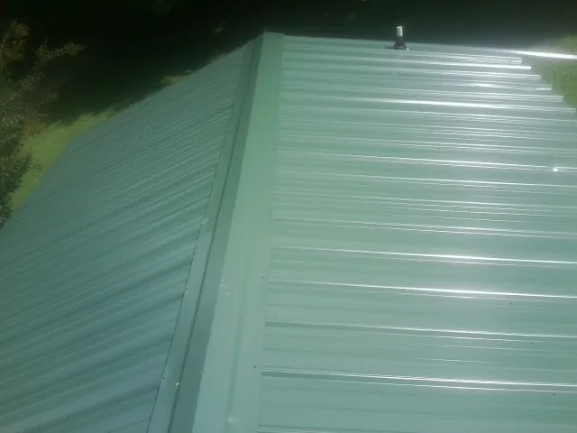 New green metal panels meeting at the ridge of a roof — Flat Roof Repair work by our crew in Langsville