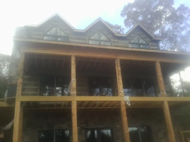 Dormers and porch framing on a large log home under construction — Roof Coating work by our crew in Langsville