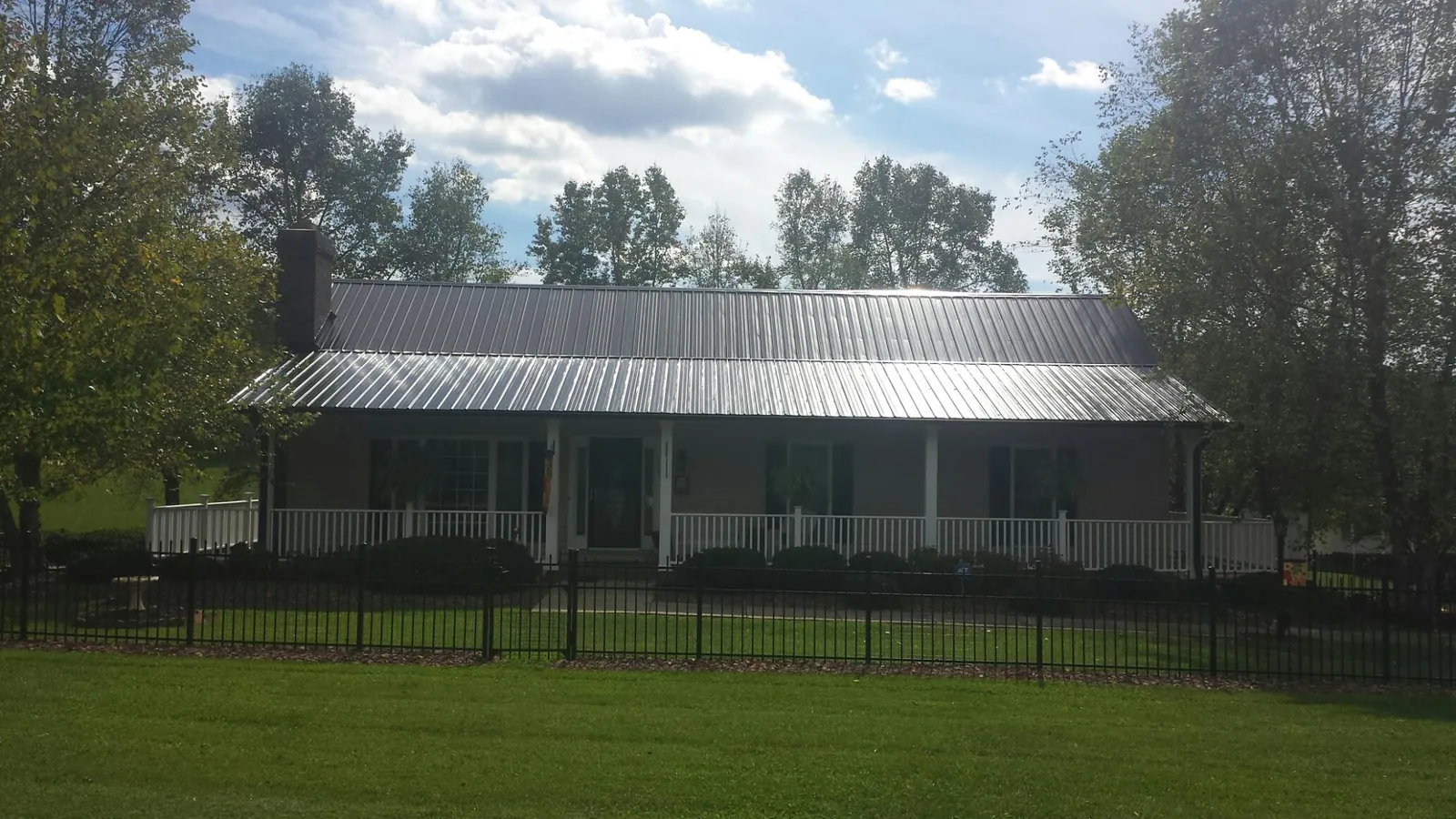 Gray metal roof on a brick ranch with a full width front porch — Gutter Guard Installation work by our crew in Langsville