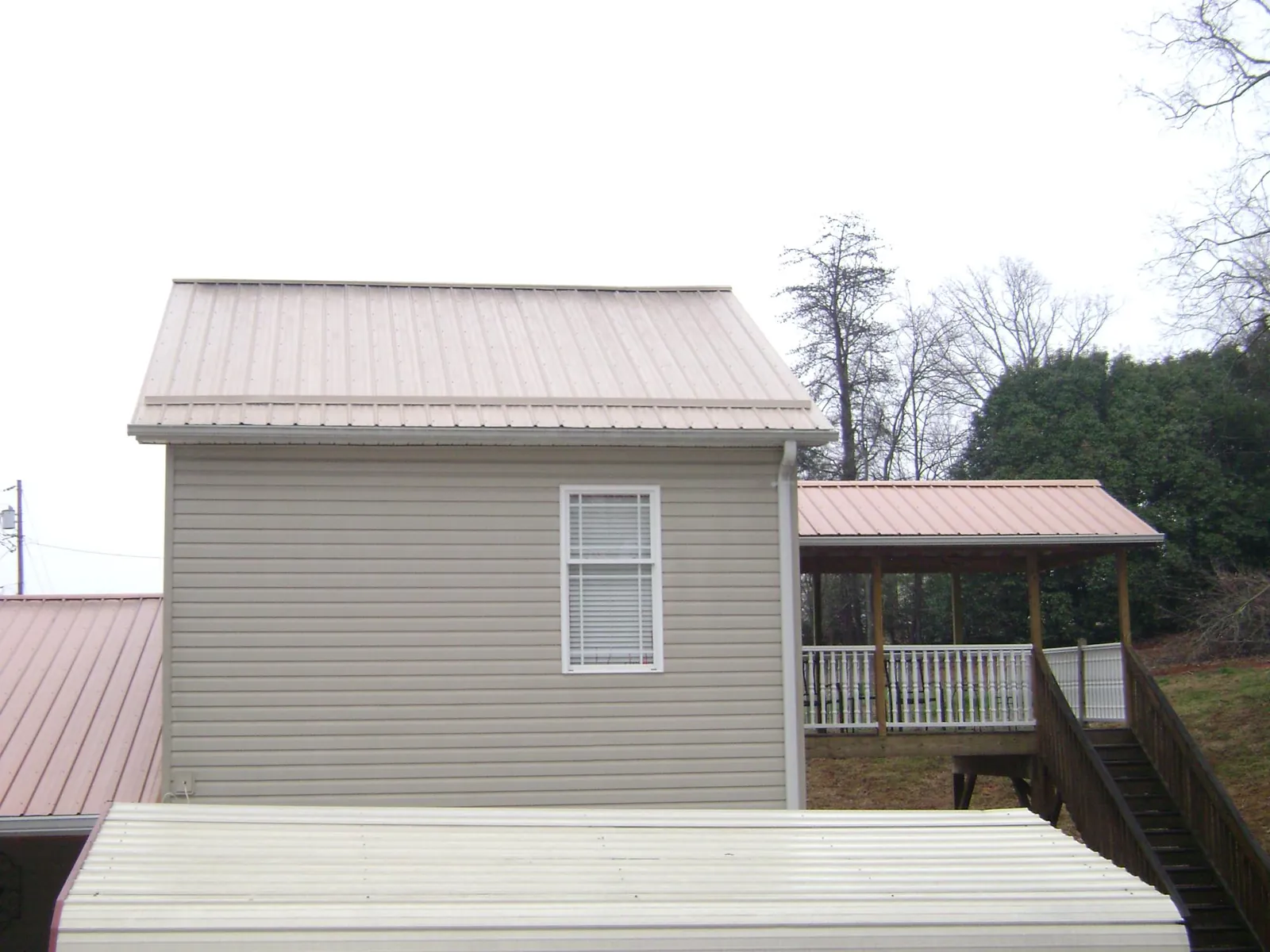 Tan metal roofs on a two story addition and attached porch, from a Roof Replacement job in Langsville