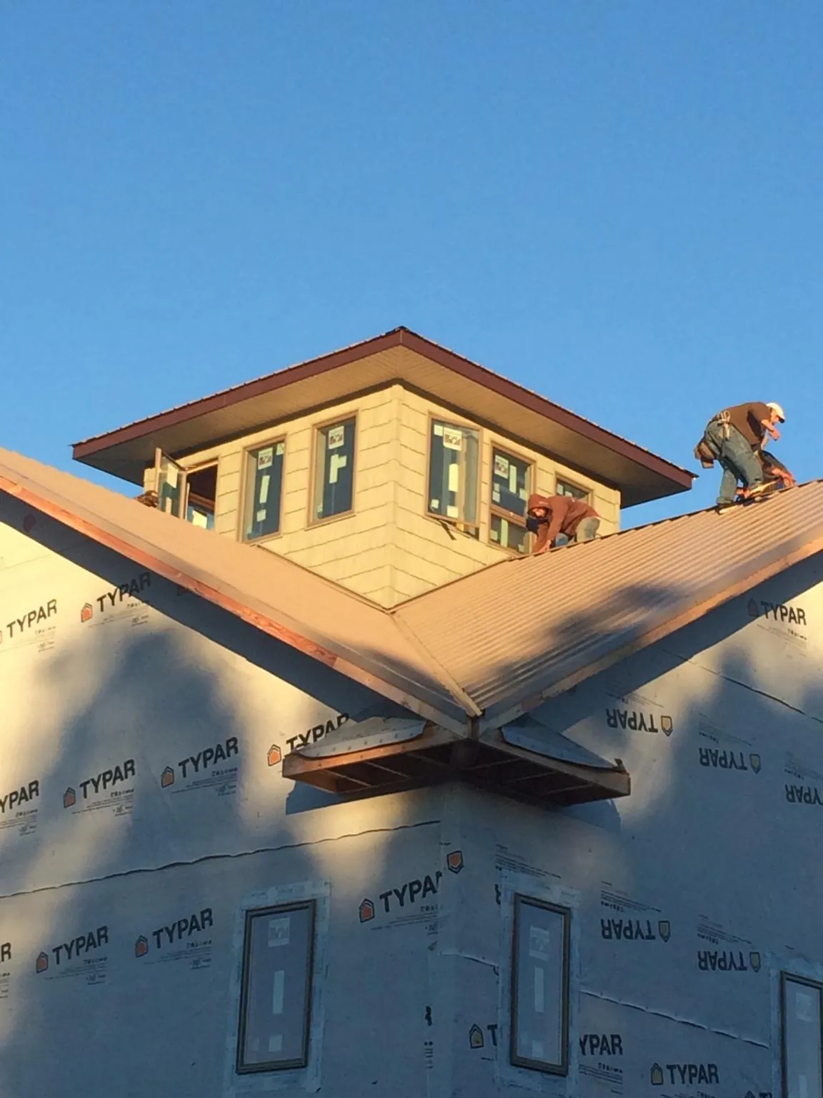 Roofers working around a rooftop cupola on a new metal roof at sunset — Roof Waterproofing in Langsville by Roofing Brothers